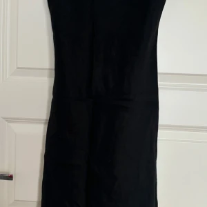 Svart klänning med pärldetaljer - Säljer en svart långklänning med smala axelband och fina pärldetaljer i blommönster framtill. Klänningen har en enkel och elegant siluett, perfekt för dig som gillar stilrena plagg med en twist. Materialet känns lätt och svalt.