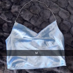 Ljusblå satin topp med kedjeband - Säljer en ljusblå topp i satin med tunna kedjeband.  Jätte fin! Säljer för 60kr