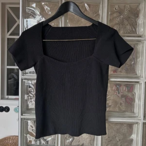 Svart kortärmad topp - Snygg svart topp med fyrkantig urringning och korta ärmar. Perfekt för en stilren look. Storlek S men passar större också!❤️ aldrig använd 
