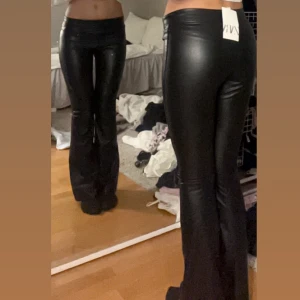 Svarta skinnbyxor med bootcut - Säljer ett par lågmidjade svarta, glansiga skinnbyxor med bootcut.☺️