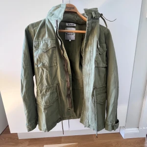 Olivgrön militärinspirerad jacka från The Gallerist - Säljer en olivgrön Field jacka från the gallerist flera fickor framtill och perfekt nu till våren o sommaren. Den är helt oanvänd då den var för liten. (Den är liten för sin storlek). Skriv gärna om funderingar😃