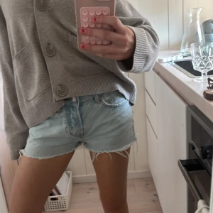 Ljusblå jeansshorts med fransar - Säljer ett par ljusblå jeansshorts med fransiga kanter. Shortsen har en klassisk femficksdesign och knappgylf. Perfekta för varma sommardagar! 🌞