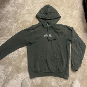 Grön hoodie med tryck - Säljer en grön vintage stil hoodie med tryck på bröstet. Slim fit. Den har en klassisk känguruficka och justerbar huva med snören. Perfekt för en avslappnad stil. Köpt på carlings. 