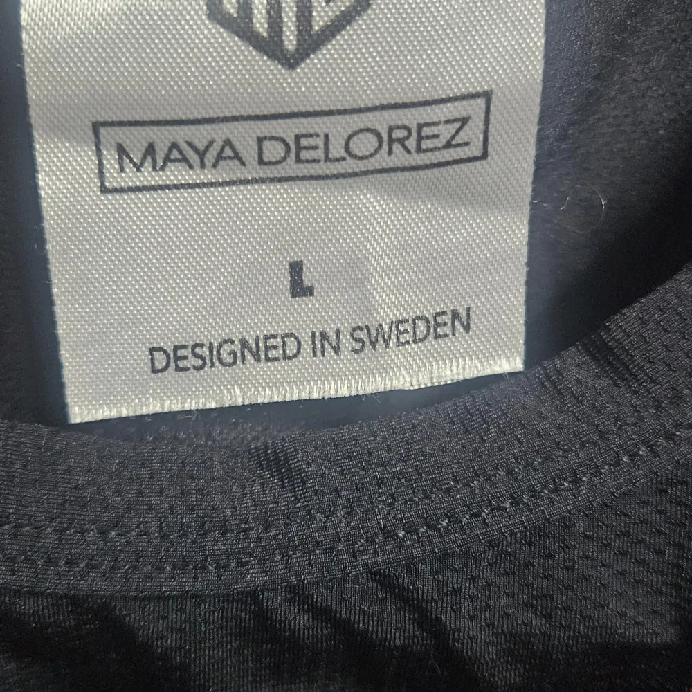 Snygg svart t-shirt från Maya Delorez med ett diskret tryck på bröstet och tre horisontella linjer på ryggen. Perfekt för en stilren look. Tillverkad i ett bekvämt material.. T-paidat.