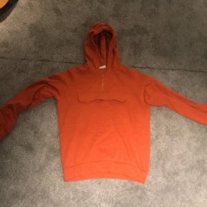 Orange tjocktröja - En orange luvtröja med magficka