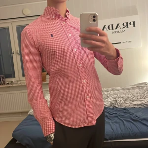 Ralph lauren skjorta  - En vit och röd Ralph lauren skjorta. Skjortan är i storlek small men skulle även passa medium och är i slim fit. Den har inga hål eller andra defekter och är i toppenskick. Hör av dig för fler bilder eller frågor.