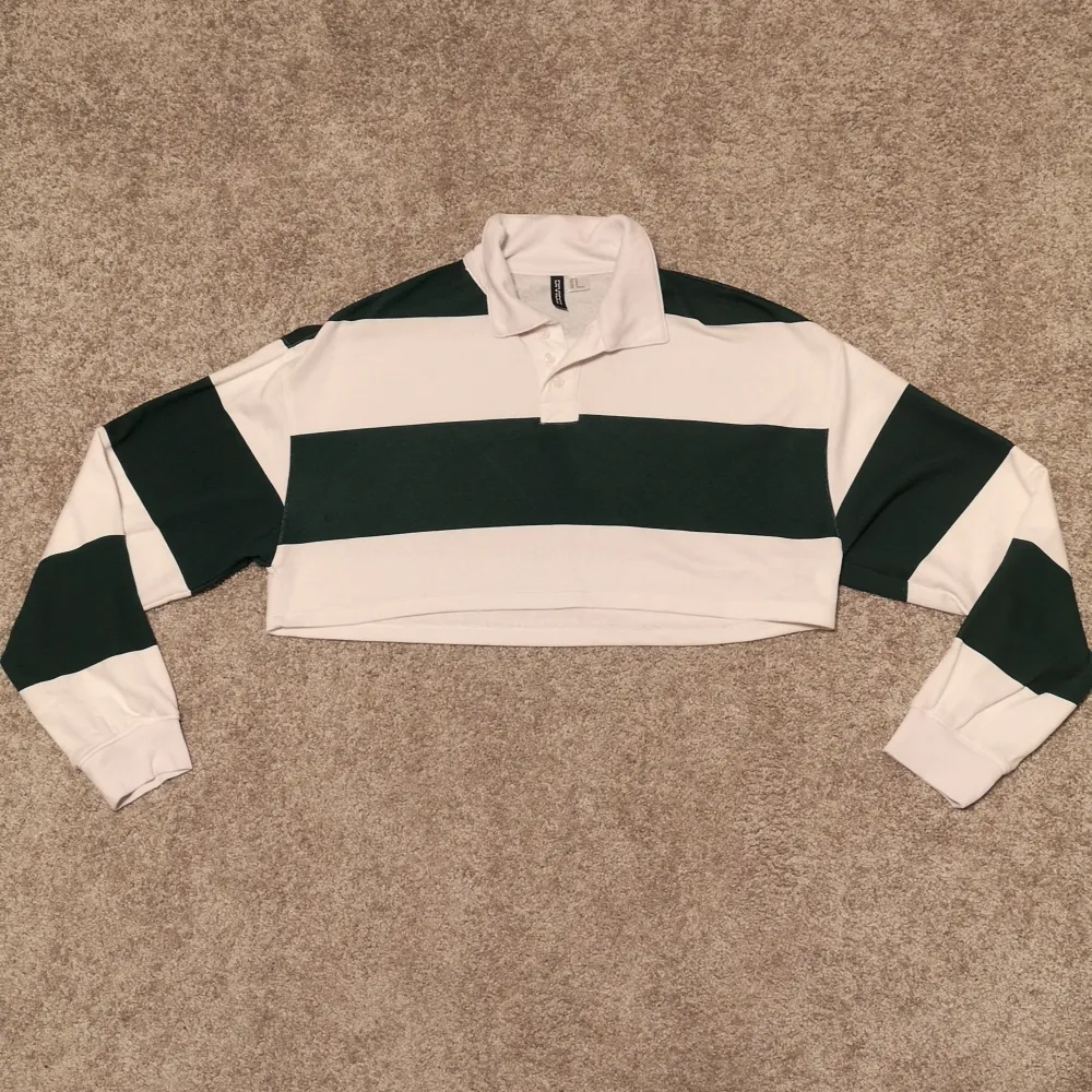 En supersnygg vit-och grönrandig tröja som är croppad och med krage. I storlek M från divided och i nyskick. Tröjor & Koftor.
