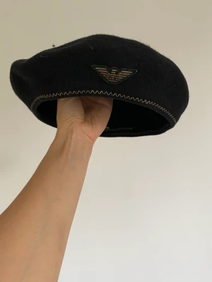 Emporio Armani Basker  - En jättefin ullbasker från Emporio Armani. Kan ej garantera äkthet då den är köpt second hand. Men väldigt fin och gott skick! Märkt storlek 59. 