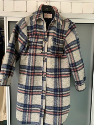 Skjortjacka  - Säljer en rutig skjortjacka i fint skick. Går till knäna ungefär. 