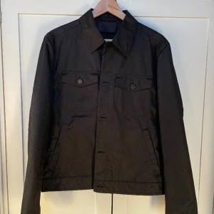 Prada Skjort-Jacka  - Svart Prada skjort-Jacka i ett mycket fint skick. Knappt använd. Säljer för ett mycket förmånligt pris. Nypris ~ 13 000kr Skriv vid frågor/funderingar! 