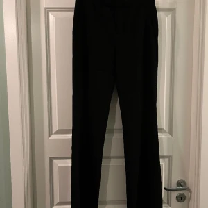 Svarta kostymbyxor  - Otroligt fin och charmig form på dessa kostymbyxor med dubbelknäppning, fickor och veckpressade. Tyget är väldigt lätt och faller därmed fint. Medelhög midja och  smått utsvängda byxben.  Aldrig använda, prislapp kvar. Nypris 500kr
