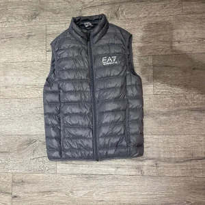 EA7 Armani väst - Säljer en skön grå Armani väst! Inte så flitigt använd, cond:9/10, Storlek: L Nypris:1600kr. Det är bara skriva vid frågor! Västen är liten i storleken, sitter som en medium väst!  