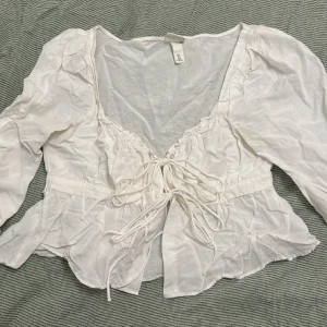 Vit topp - Topp från H&M x Brock Collection. Fin med snörning där fram och detaljer vid urringningen. Använd 1-2 gånger. 