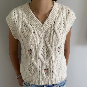 Stickadväst - Gullig stickadväst med små blommor på. Den är i storlek 152 men är stor i storleken och passar till xxs-xs. 