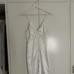 Vit klänning - Vit satinkläning från Biancas collektion med Nelly. Storlek XS. Har endast provat men annars oanvänd. Köparen står för frakten, kan också mötas upp i Gbg 💕