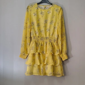 Klänning - Gul volangklänning med blomtryck på i chiffong. I nyskick.