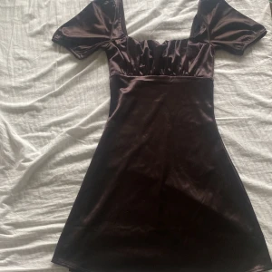 satin klänning - säljer nu min favortiklänning då den blivit för lite över börstet! köptes 2020/2021. svårt att förklara färgen men den är lite brun/svart/grå! 