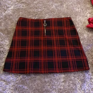 Rutig kort kjol. - En röd svart rutig kort kjol, använt någon gång, jättefin men behöver rensa ut lite.