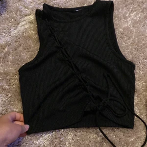 Svart topp. - En sexig svart topp, jättesnygg typ aldrig använt. Den är öppen från axeln och neråt.