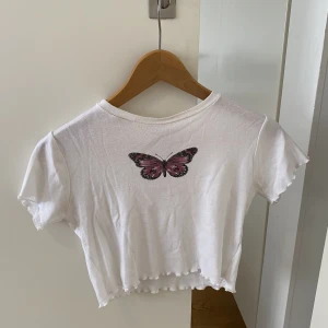 Gullig topp med fjäril - Vit croppad t-shirt med fjäril. OBS - håll i kragen men går att sy. Skriv för bild.  