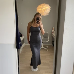 Långklänning - En as söt mörkgrå långklänning i storlek S, helt ny och använd, tight och formar kroppen fint men lite utåt där nere vid benen🤍🤍