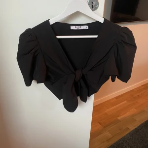 Kort svart topp med små puffaxlar.  - Svart kort topp från NA-KD. Använd 1 gång. 