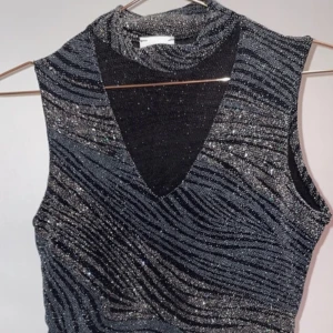 Glittrig topp - Glittrig topp som har som en choker del! Toppen har som ett tigermönster i blått och silvrigt