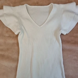  ribbad topp med volanger  -  ribbstickad volang topp som är kortärmad i krämvit färg 🥰