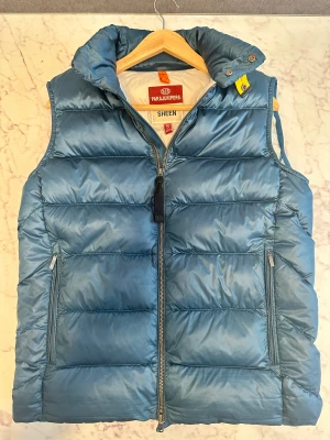 Parajumpers vadderad väst med logotyp - Tjena säljer denna unika  Parajumpers väst. Den är i fint skick och kommer att bli ett utmärkt tillägg till din garderob. Tveka inte på att kontakta mig ifall du undrar något eller vid intresse.