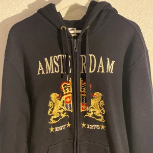 Blå Amsterdam hoodie - Zip up hoodie med texten Amsterdam. Storleken är XL men passar nog bättre som L 