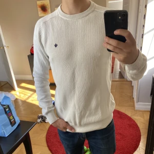 Vit stickad Morris  - Det är en fin stickad tröja som kommer värma dig från och med slutet av sommaren till början av nästa. Modellen i bilden är 177Cm. Har bara använts ett par gånger. Skicket på tröjan är som ny med inga defekter.  