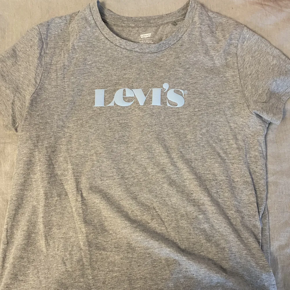 En fin grå Levis t-shirt med blått tryck, andvänd ca 2 ggr i strl M/L . T-shirts.
