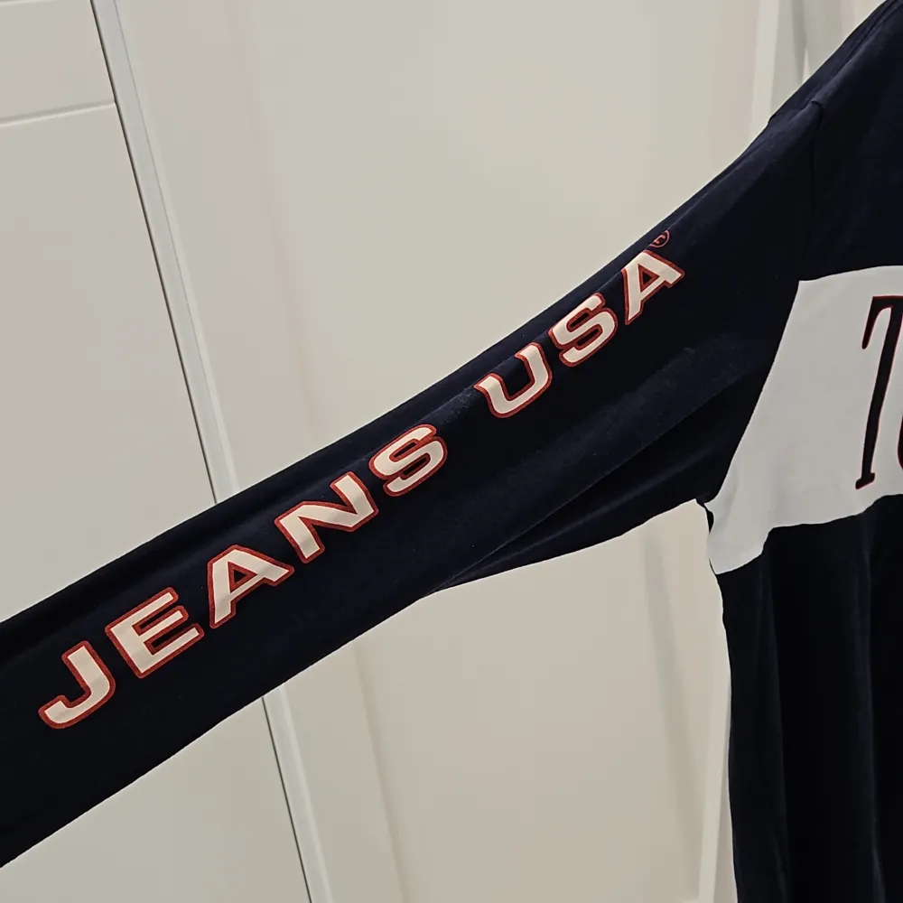 Det är en tun tröja med märket tommy jeans  På högra armen står det jeans USA  Mörkblå . Hoodies.