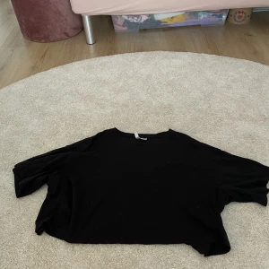 Svart croppad T-shirt!  - Den har långs ärmar för att vara en T-shirt och är hel svart. (porto tillkommer)