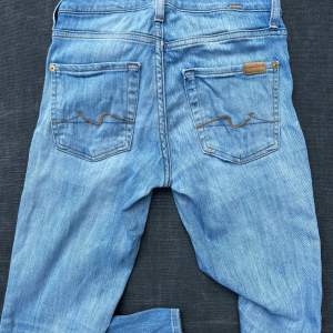 Raka seven jeans med låg midja i strl 23. Supersnygg slitning. Sömnen har släppt på ena fickan, enkelt fixat med en symaskin. Strl passar en 25. 