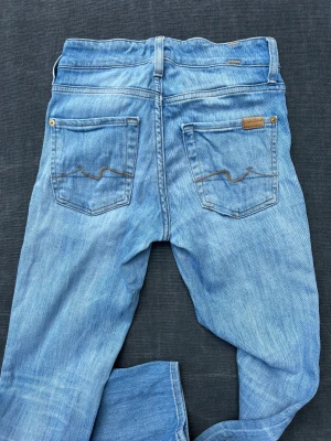 Low waist - Seven jeans  - Raka seven jeans med låg midja i strl 23. Supersnygg slitning. Sömnen har släppt på ena fickan, enkelt fixat med en symaskin. Strl passar en 25. 