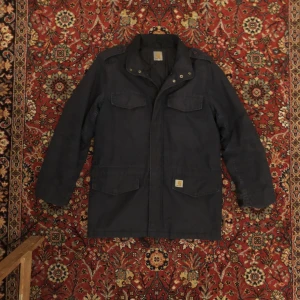 Carhartt Vinterjacka - Vintage carhartt jacka.  Varm och bekväm. Passar perfekt för de kallare månaderna på året.  Jackan har tecken på användning men är i gott skick utan defekter.  Sitter som en vanlig strl L.  Skriv gärna för mer info eller bilder!  :) 