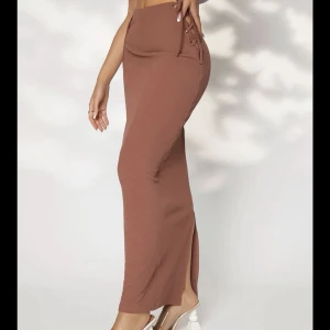 Långkjol med slits - oanvänd - Oanvänd kjol med slits i baksidan. Den har två knytning på bägge sidorna som man själv kan justera. Köpt för 250kr, säljer för 130kr. Priset kan diskuteras👍🏼den är ljusbrun