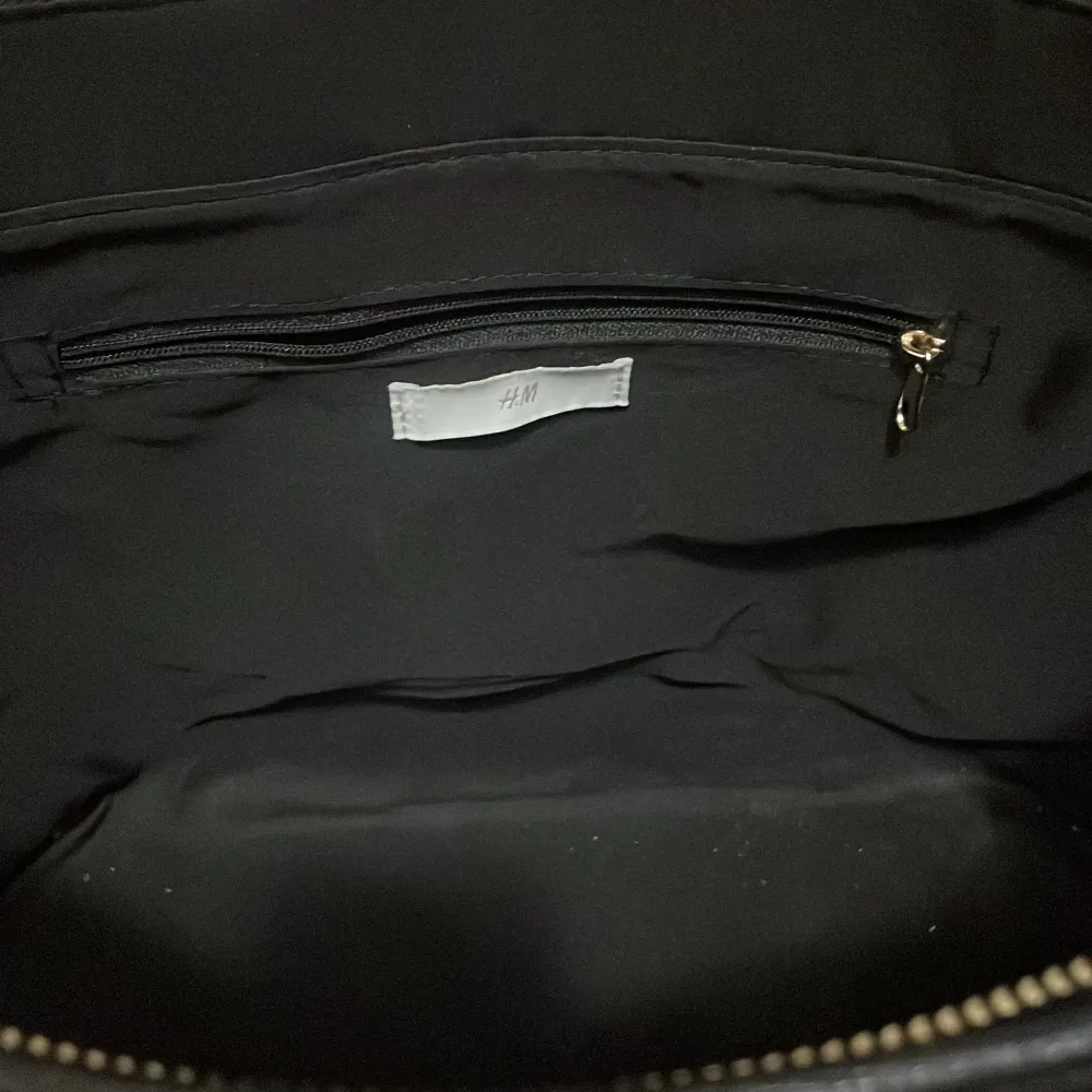 Stor svart handväska från HM med guldig dragkedja. Väskan är i nyskick. . Väskor.