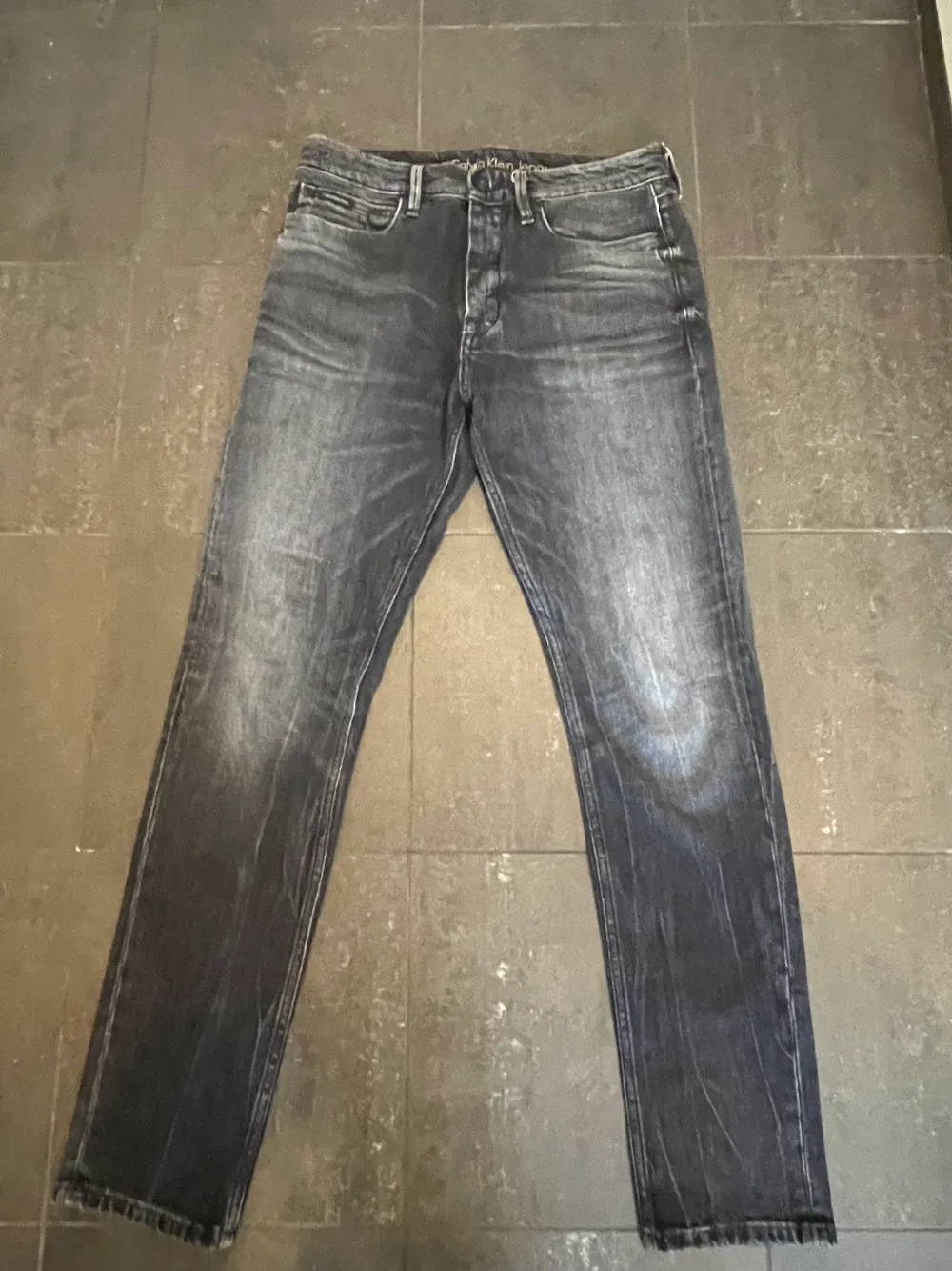 Säljer dessa stiliga Calvin Klein Jeans i modell Taper. De är svarta med toner av grått. De har använts vid få tillfällen och är därför i ”mint condition”. Storleken är 30/32. Hör av dig vid frågor eller funderingar.. Jeans & Byxor.