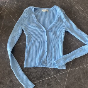 Ljusblå topp - Ljusblå topp från H&M. Stretchigt tyg med knappar. Passar storlek 34-38.