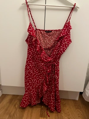 Klänning med hjärtan - Klänning med omlott röd med vita hjärtan. Man knyter själv med repet så storleken går att anpassa😊