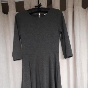 Grå klänning - Grå klänning från gina tricot. Den är i fint skick men för liten för mig. Klänningen är halvlång och ärmarna är trekvarts, marerialet är lite tjockare så värmer bra. Den är även strechig så sitter väldigt fint på.