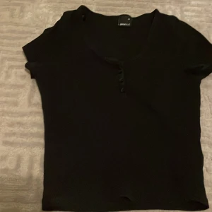 Svart topp - Toppen är från ginatricot och är använd ett par gånger. Tvättad. Toppen är svart med små knappar framtill.