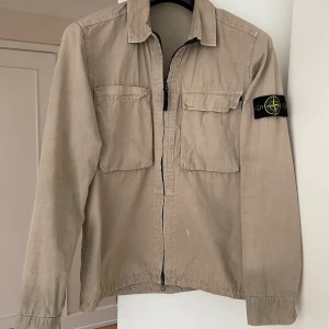 Stone Island Overshirt Beige - Overshirt i beige från Stone Island, perfekt nu till våren🔥Storlek medium. Köpt för 3099kr. Två bröstfickor med dragkedja. Liten fläck på framsidan, går att se på bilden. Annars utmärkt skick!