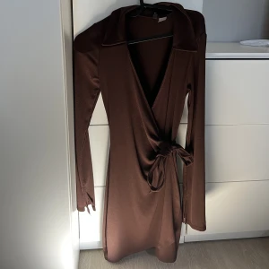 Klänning  - En jätte fin brun klänning som man själv kan knyta på sidan! Använd ca 2 gånger och sitter så fint. Säljs pågrund av ingen användning.