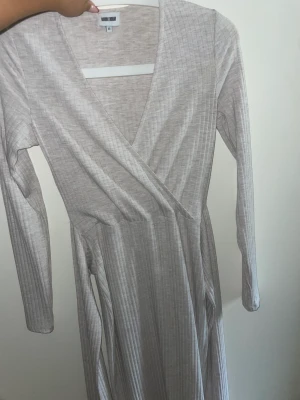 Klänning  - En begie,grå,rosa klänning som går att spänna åt vid midjan. Köpt på bubbelroom för cirka 3 år sen och andvänds Max 10 gånger. Bra skick.  Kontakta vid frågor m.m..