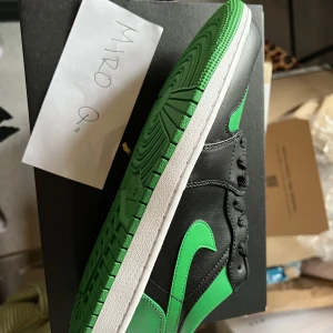 Air Jordan 1 Low 'Black Lucky Green’ - Endast sälj!!!  Helt nya / Äkta skor Original låda och kvitto medföljer. Skriv om du har frågor om priset, flera bilder, etc. Va inte blyg ☺️ 
