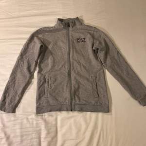 Det är en äkta hel grå zip hoodie från Emporio Armani som inte har några håll eller utmärkelser på sig, den har två styckna fickor på utsidan och två styckna innerfickor, den är storlek 160,  Du får budda det du vill så får jag se om det blir bra