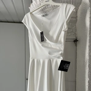 Studentklänning  - Vit klänning från Nelly i storlek S. Aldrig använd, prislapp kvar. Skickas med frakt.